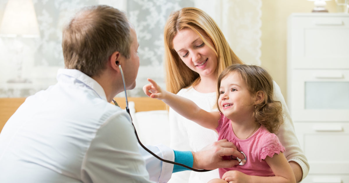 a doctor diagnosing a cute baby girl in the lap of her mother